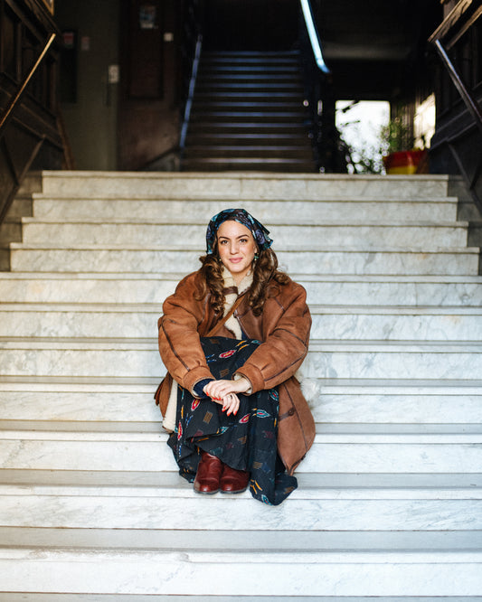 A woman sitting on steps wearing bohemian winter outfit